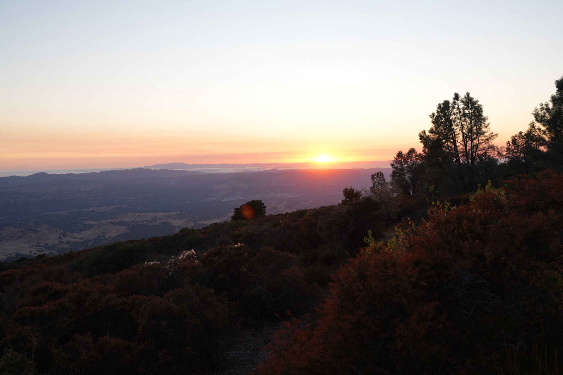 The sun setting behind the Bay Area hills from the slopes of Mount Diablo, the sky turning deep orange